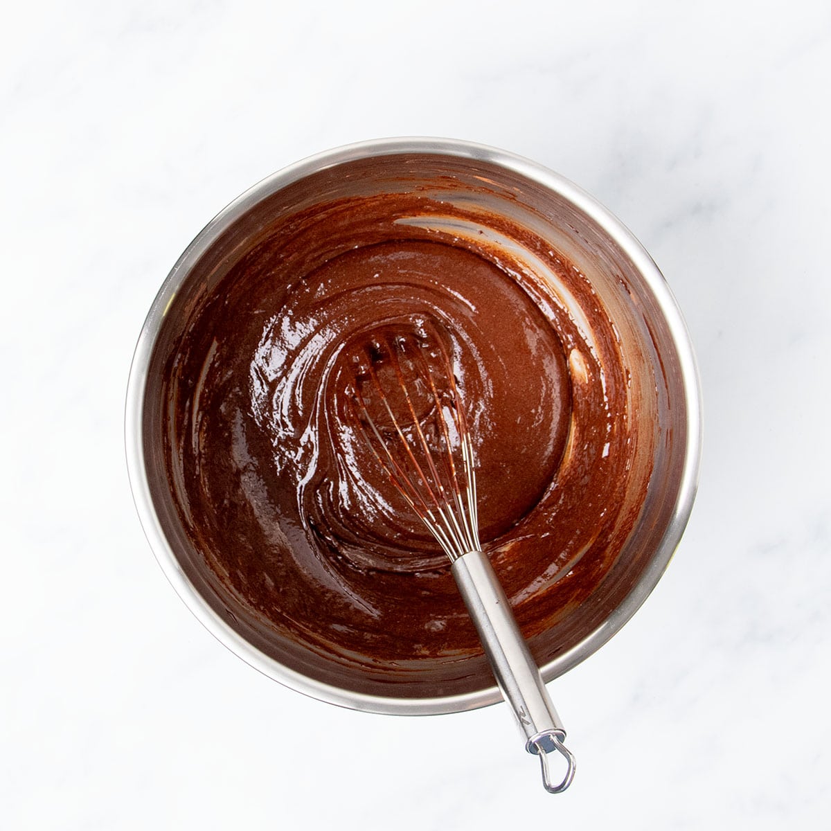 same mixing bowl with whisked brown chocolate ingredients with wire whisk