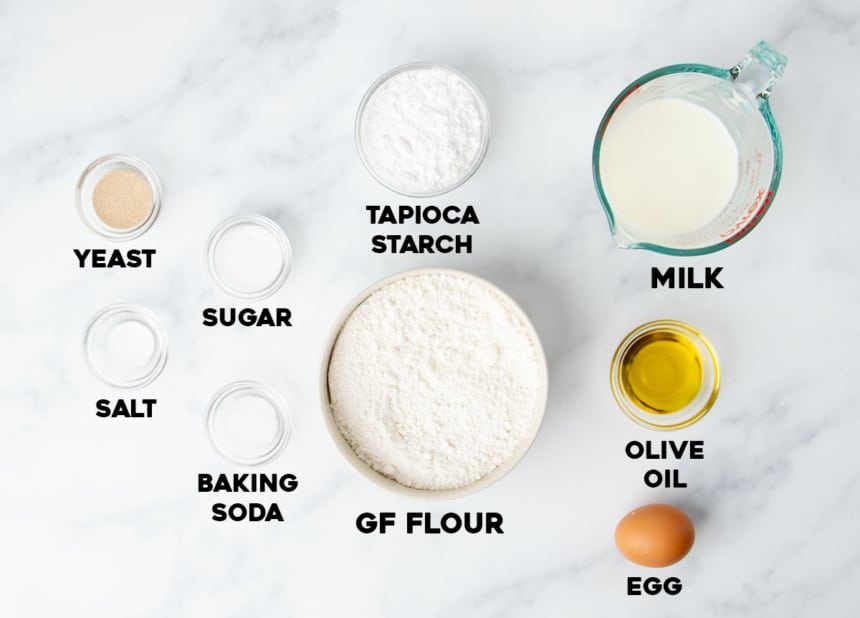 overhead image of ingredients for gluten free artisan bread in small bowls on marble surface with words for names of each one