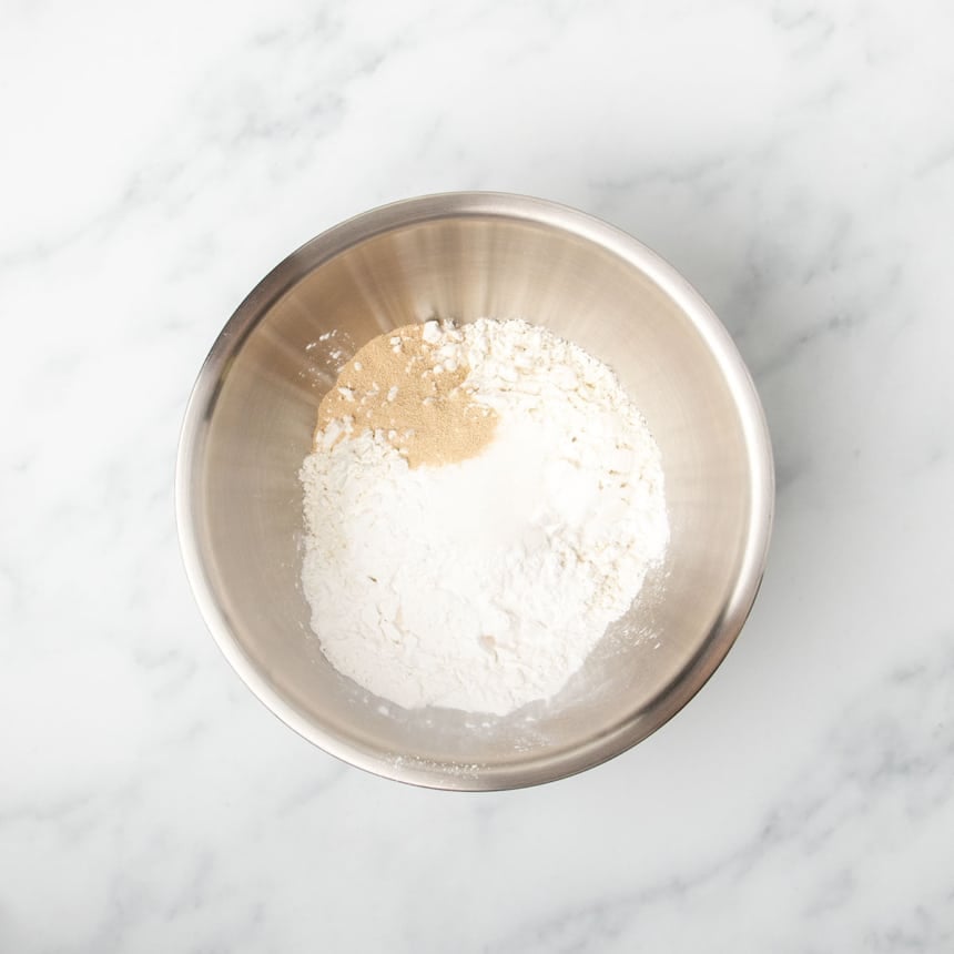 round metal mixing bowl with white and tan dry powdered ingredients unmixed