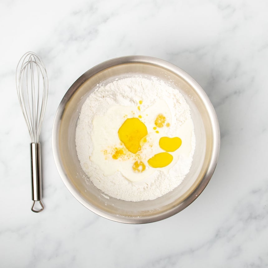 yellow olive oil and beaten egg and white milk on top of whisked dry ingredients in same bowl