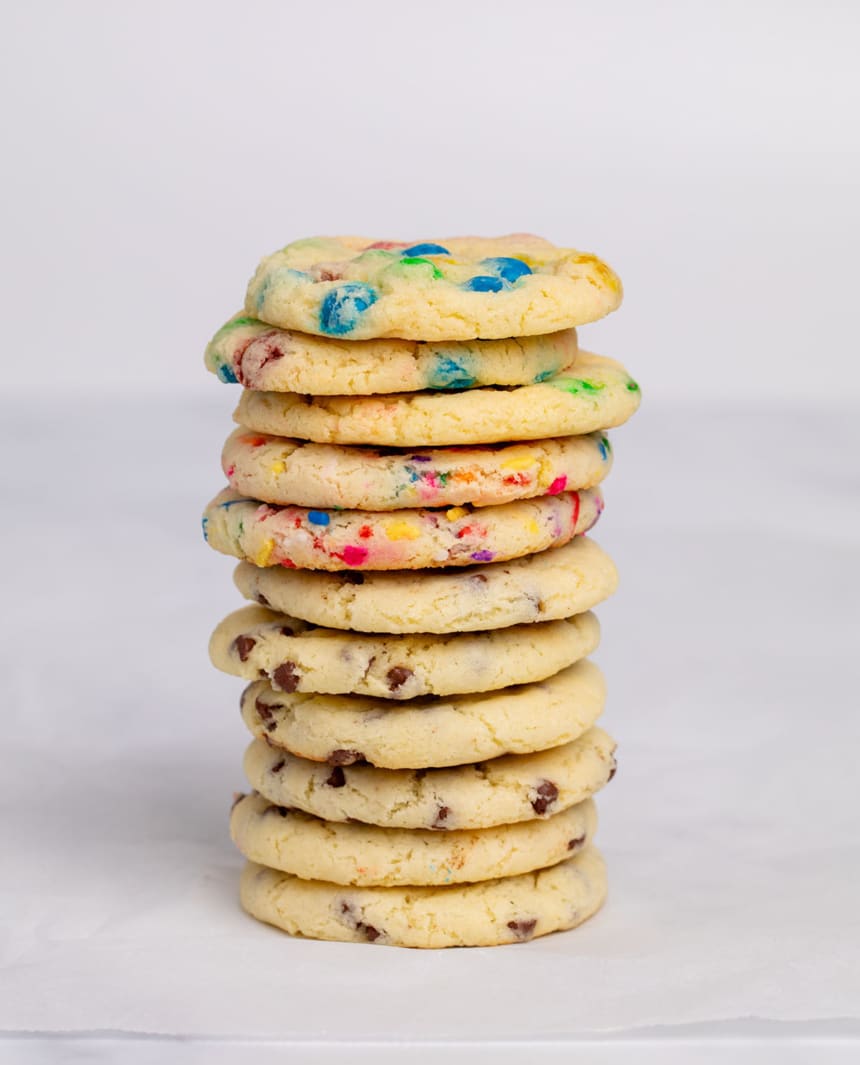 tall stack of 11 gluten free cake mix cookies with different mix ins on white paper