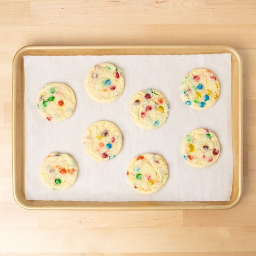 8 baked light yellow cookies with colored candy pieces on baking tray