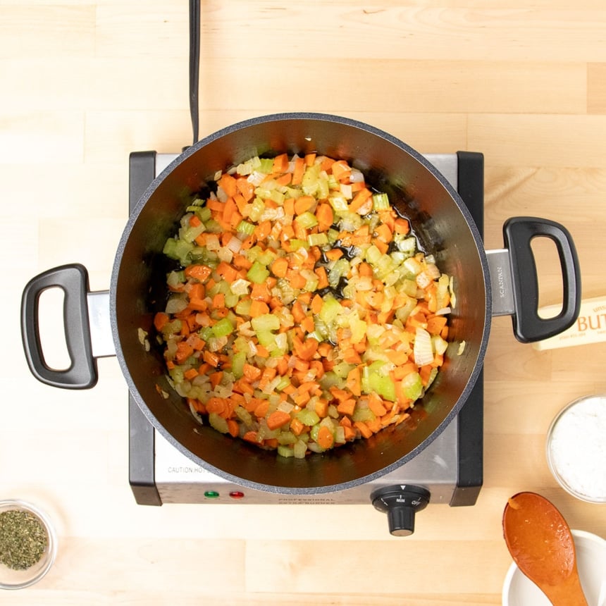 cooked chopped carrots, celery and onion in oil in black pot