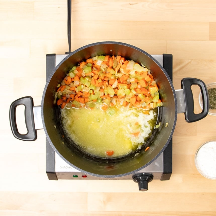 cooked vegetables pushed to the side in the same black stockpot with melted butter and flour