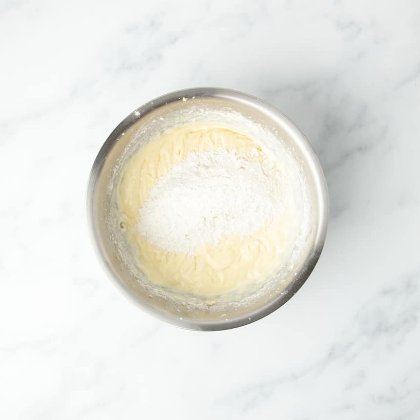 Light yellow batter in mixing bowl with more flour on top