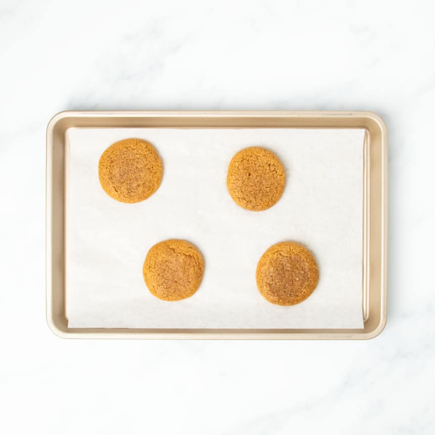 same baking sheet with 4 gluten free molasses cookies now somewhat darker brown and baked