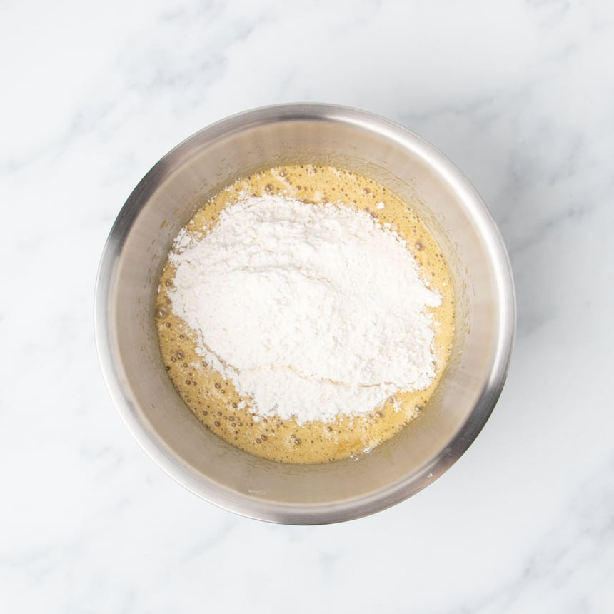 White flour mixture on top of light brown mixture in mixing bowl