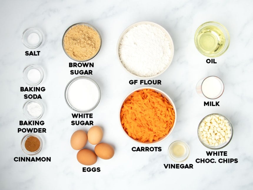 ingredients for gluten free carrot cake in small bowls with names of ingredients in black typeface