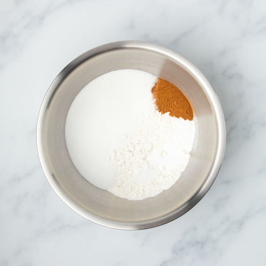 Large round metal mixing bowl with white powders and some brown cinnamon powder