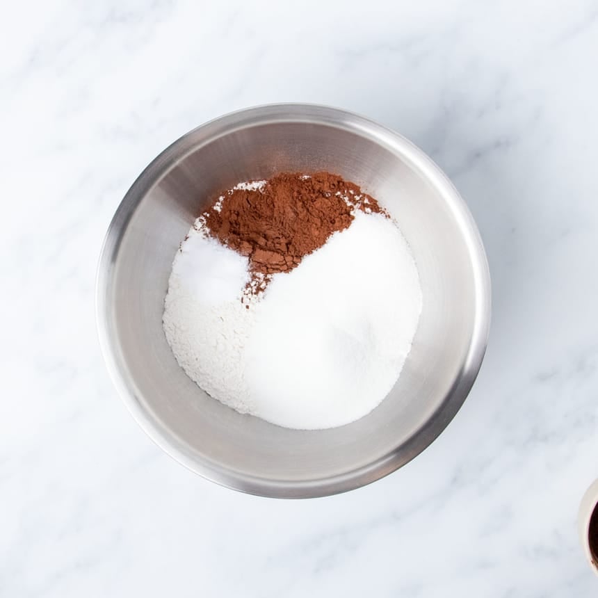 large round metal mixing bowl with white powders and some brown cocoa powder