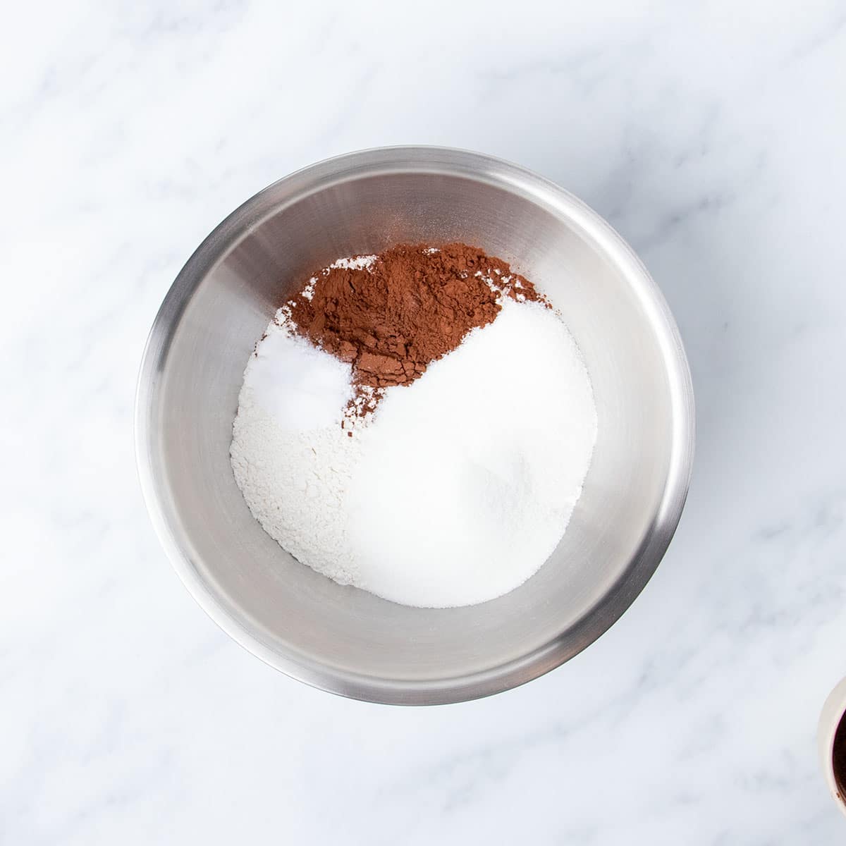 large round metal mixing bowl with white powders and some brown cocoa powder