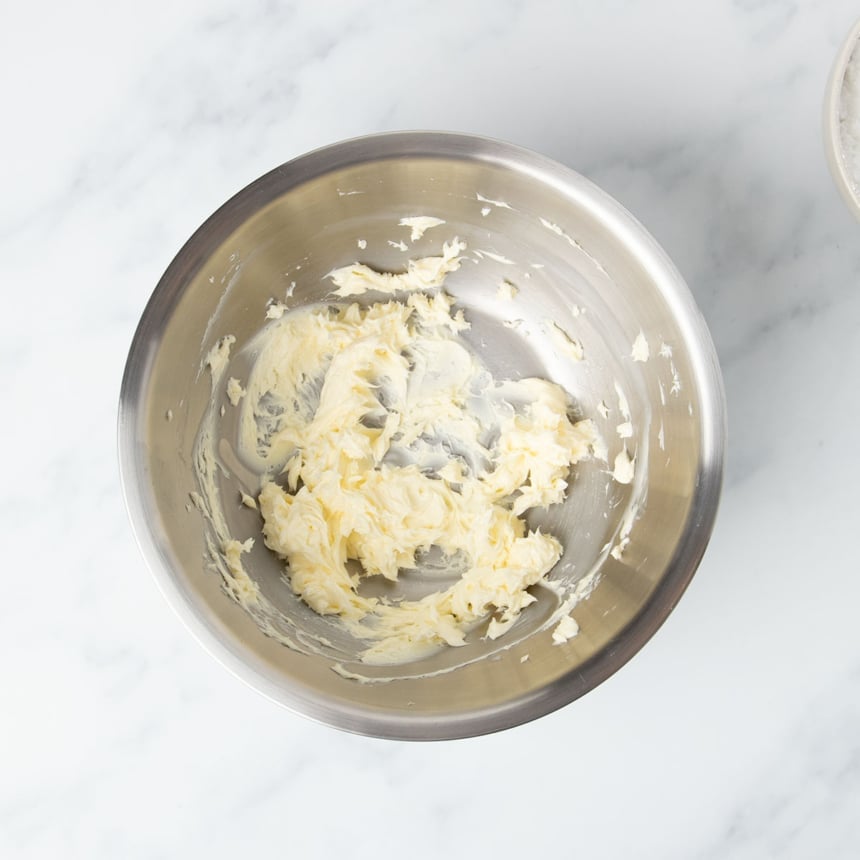 whipped light yellow butter in large round metal mixing bowl