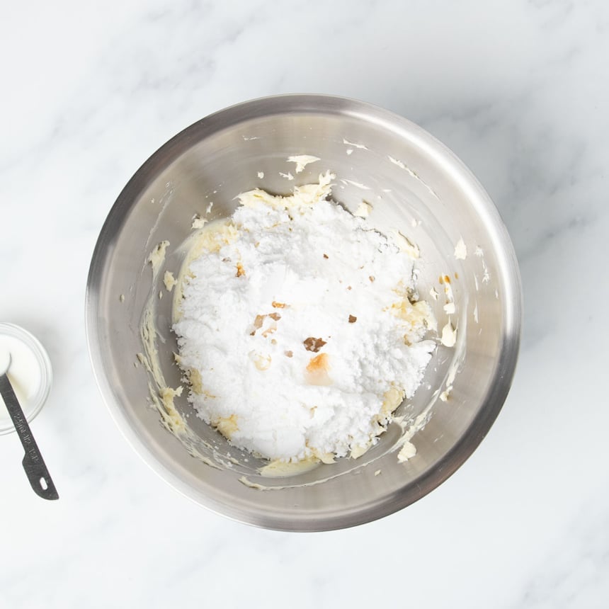 same mixing bowl with confectioners' sugar, vanilla and some milk on top