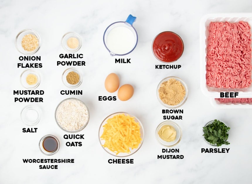 overhead image of ingredients for gluten free meatloaf in small bowls on marble surface