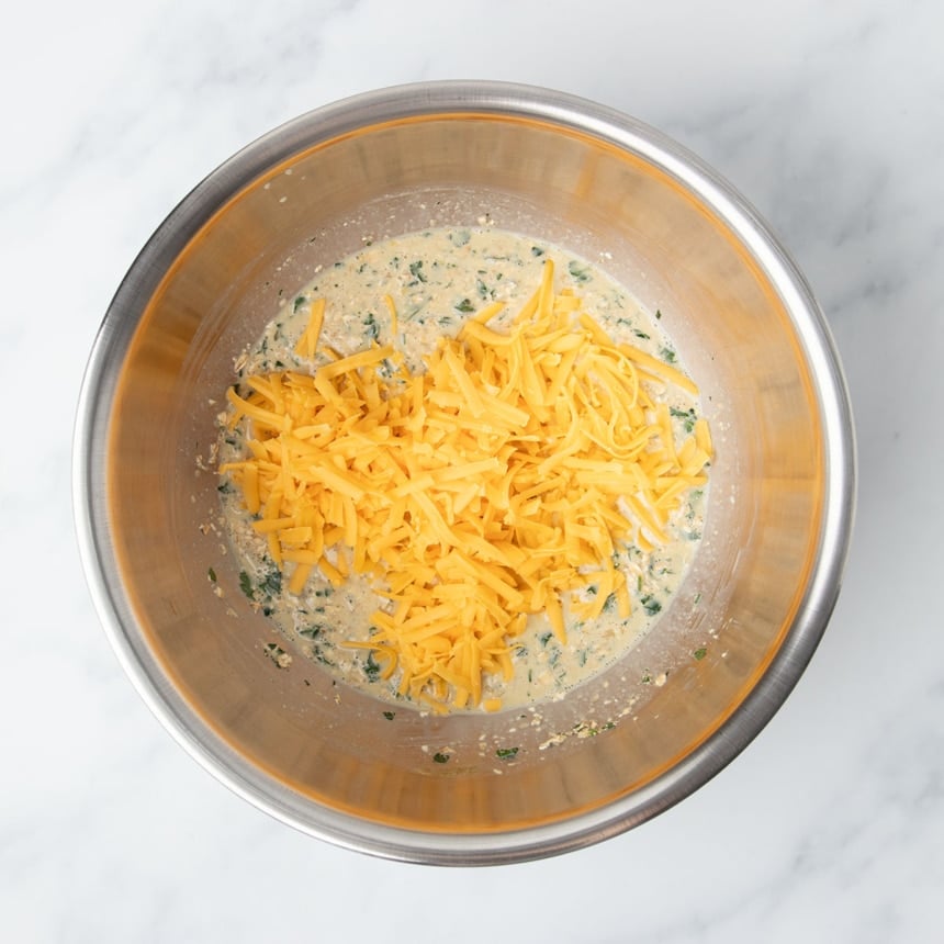 shredded yellow cheddar cheese on top of wet mixture