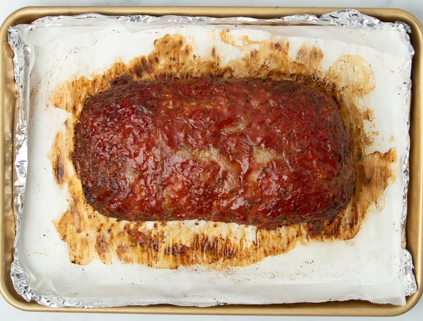 whole baked meatloaf on white paper on pan