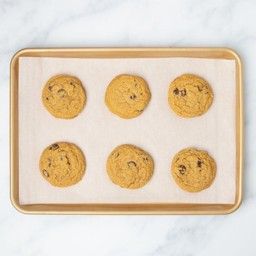 same 6 balls of cookie dough baked into 6 round light orange-brown gluten free pumpkin chocolate chip cookies