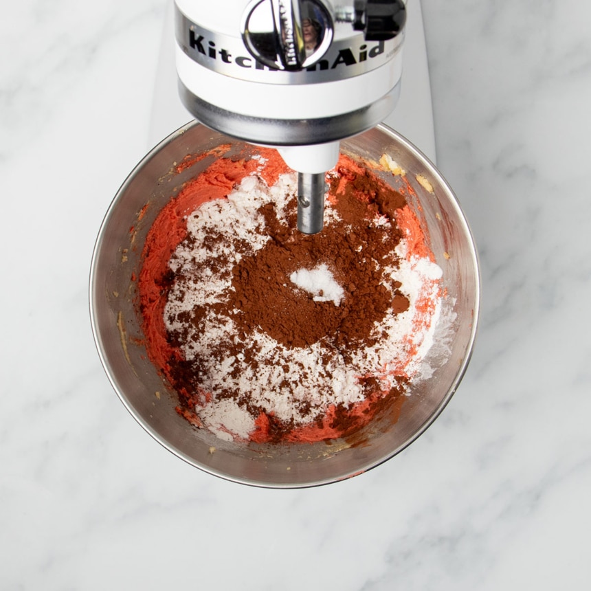 brown cocoa powder and white flour on top of red mixture in bowl