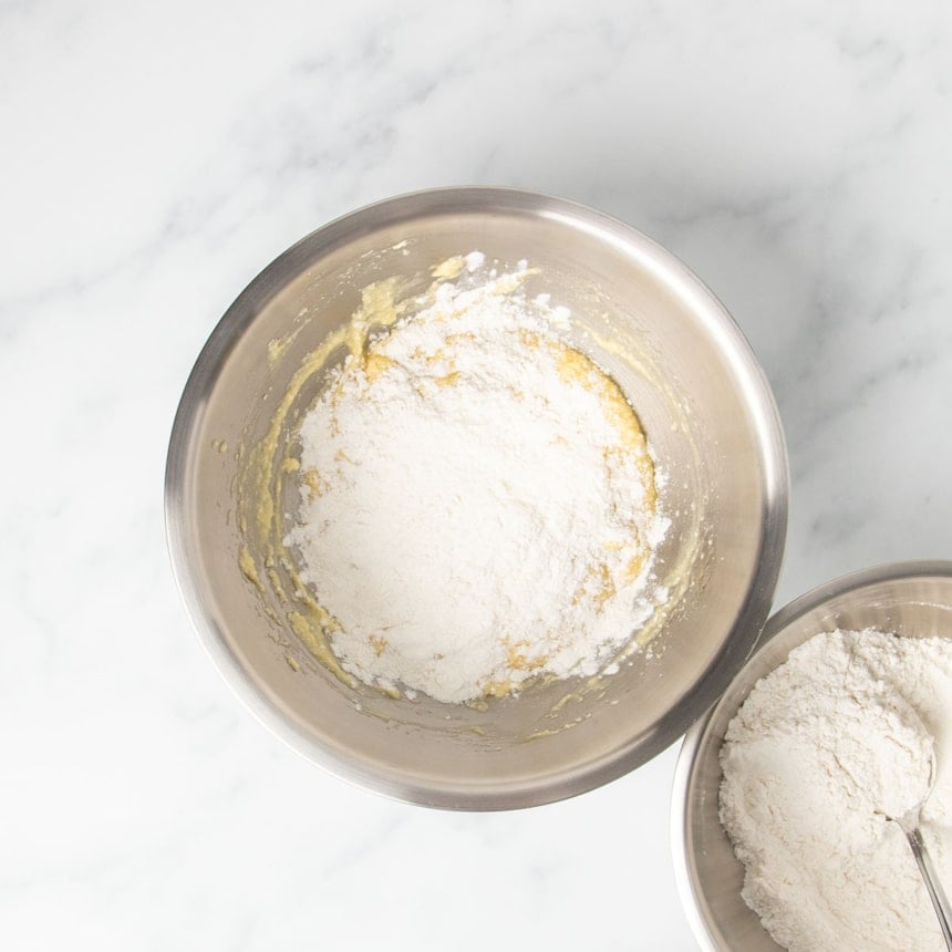 white powder dry ingredients unmixed on top of yellow butter and egg mixture