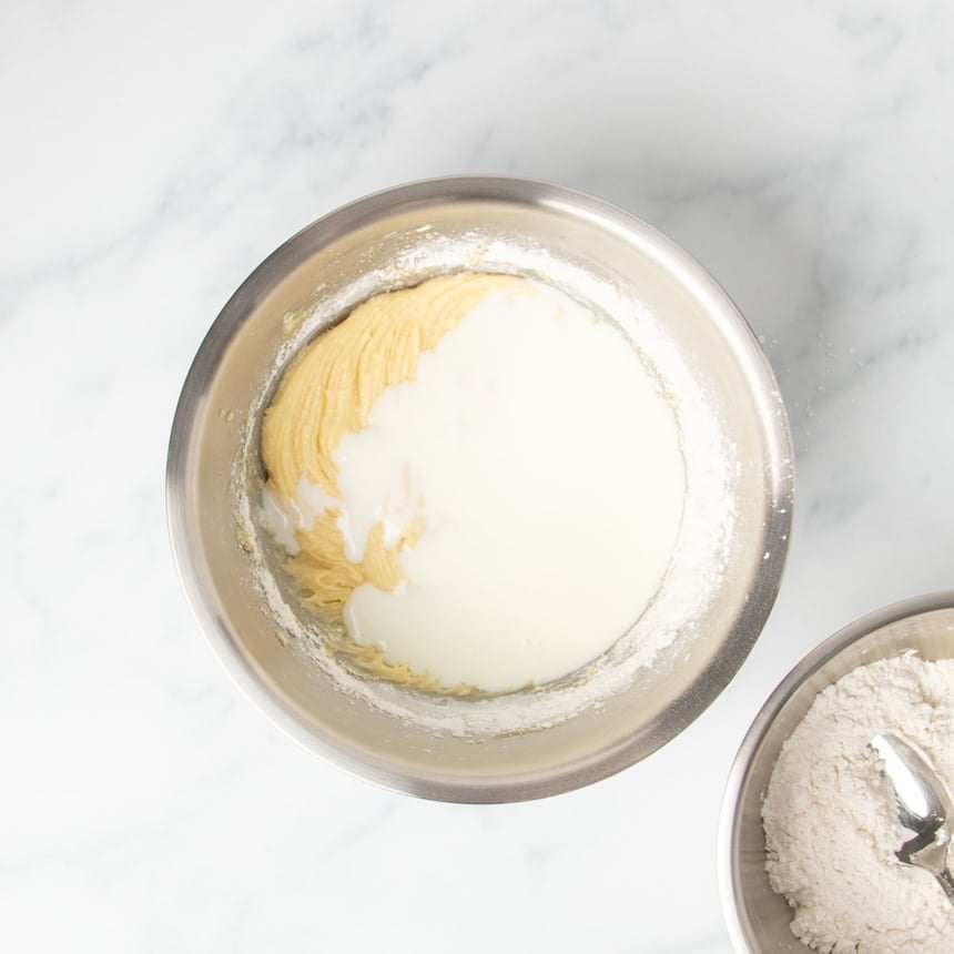 white buttercream unmixed on top of yellow cupcake batter in mixing bowl