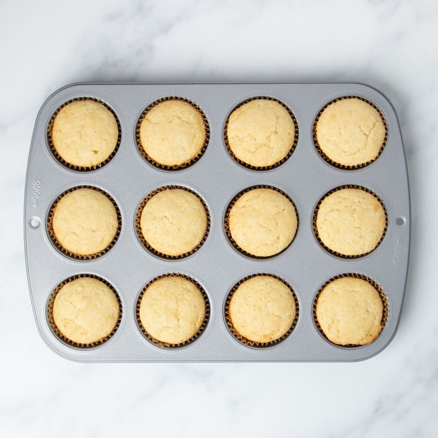 same cupcake tin with baked vanilla cupcakes in wells