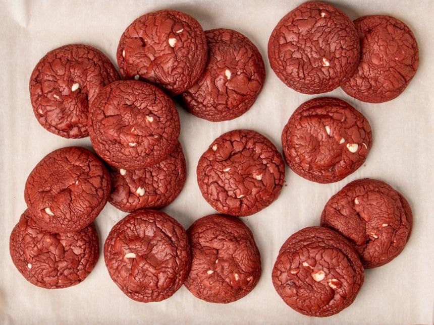 Overhead image of pile of gluten free red velvet cookies with white chocolate chips on white paper