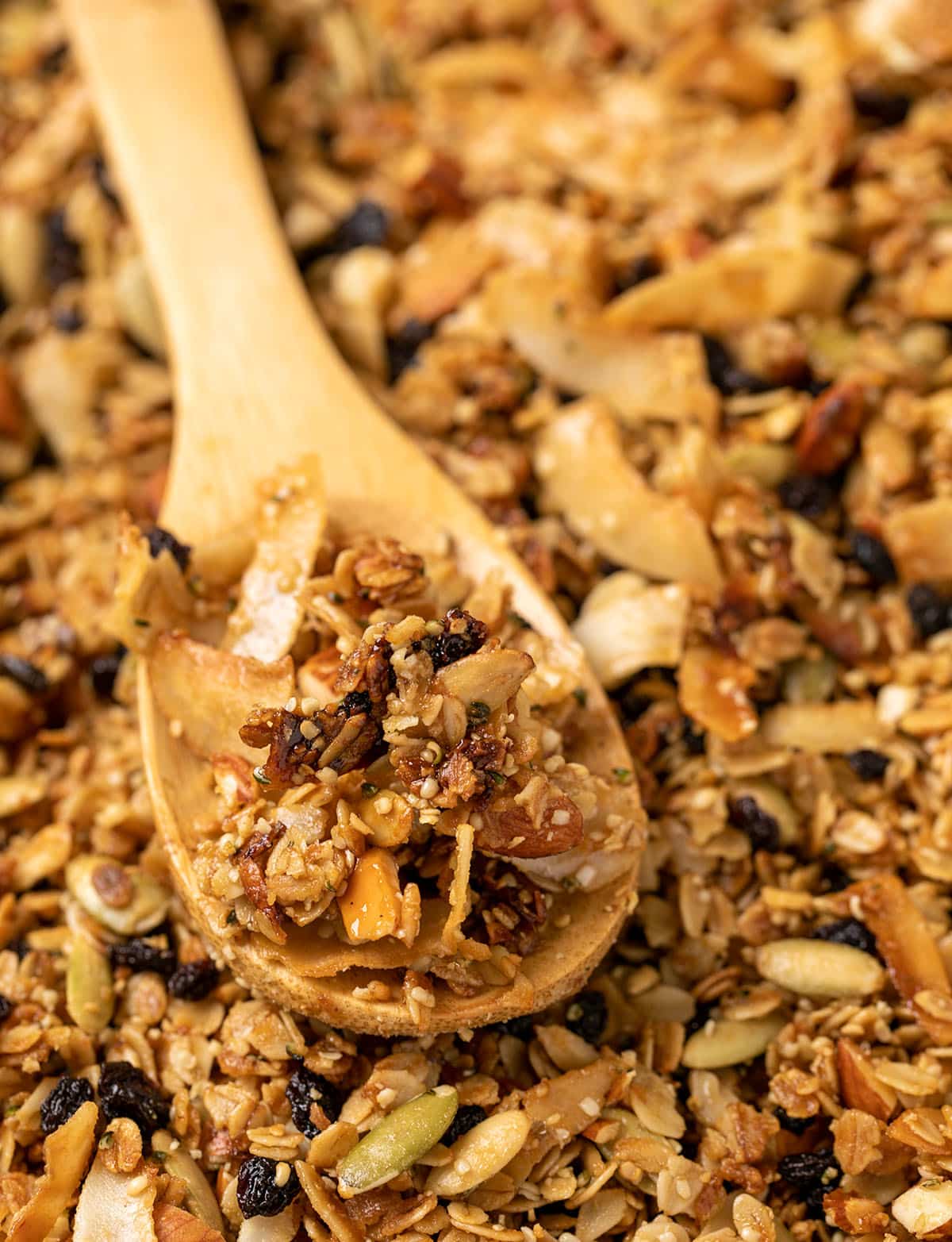 brown baked granola on tray with some on wooden spoon