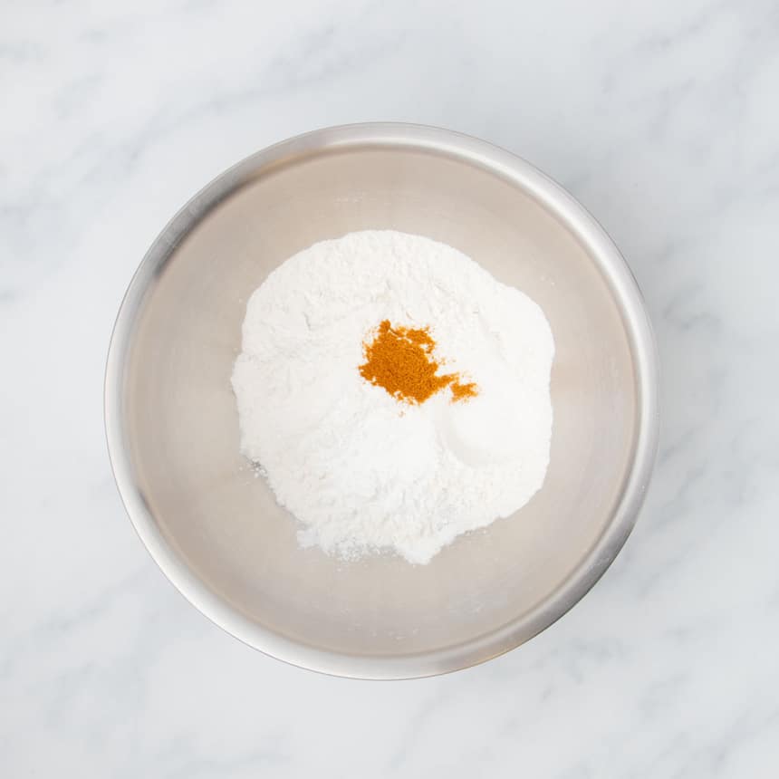 large round metal mixing bowl with white powder with the orange-brown color of paprika on top