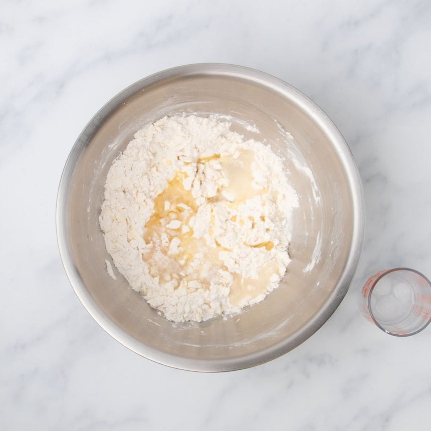 same bowl with butter shreds mixed in to white powder, with water and oil sitting on top