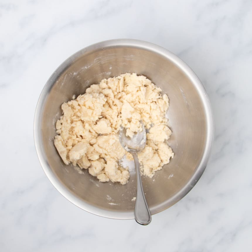 clumps of off-white mixed cracker dough in same bowl with same spoon