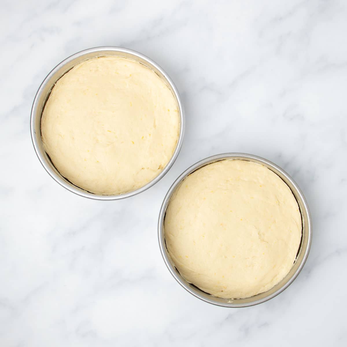 two 8-inch round metal cake pans with half of the cake batter in each, smooth on top