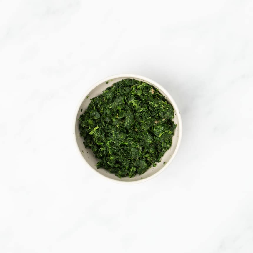 dried green chopped spinach in small light tan bowl