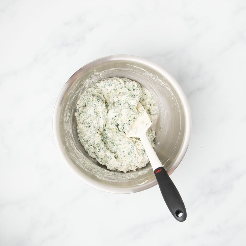 same bowl with everything mixed into thick white and green flecked mixture with white silicone spatula with black handle