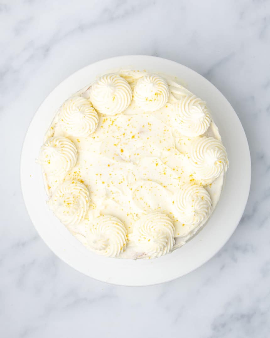 Overhead image of frosted lemon cake with frosting swirls and sprinkled lemon zest