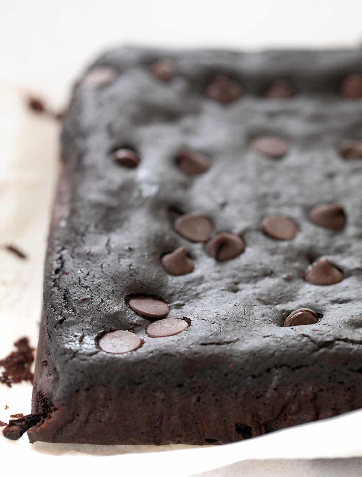 The brownies out of pan uncut on white paper.
