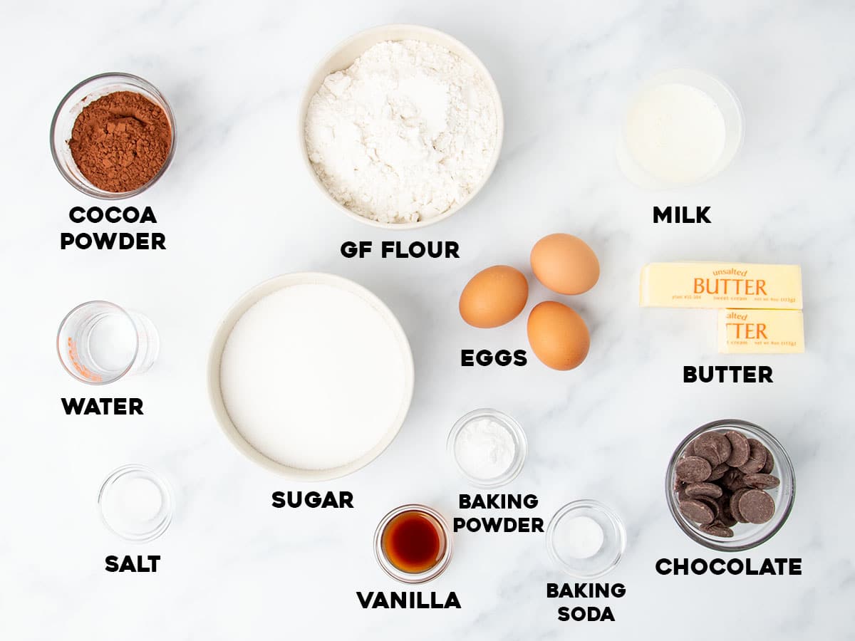 overhead image of gluten free chocolate bundt cake ingredients in small bowls with black block letters with names of each listed
