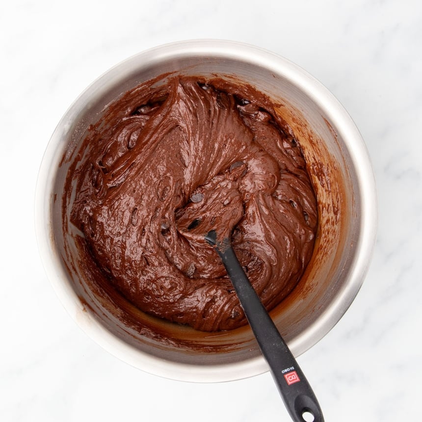 Same bowl and spatula with chocolate chips mixed in to raw chocolate muffin batter