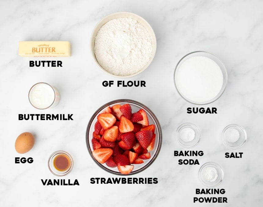 ingredients for gluten free strawberry cake in small bowls with black block lettering with ingredient names