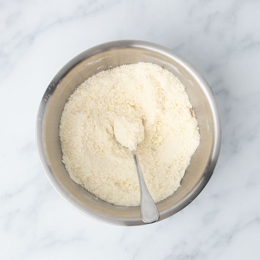 Same mixing bowl with very pale mostly dry yellow mixture of flour with butter mixed in