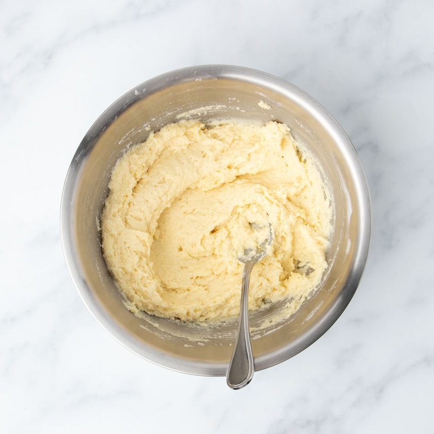 thick raw light yellow cake batter in mixing bowl with mixing spoon