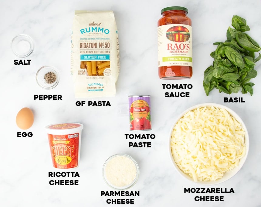 ingredients in gluten free baked ziti in small bowls and containers with bold black type with names of ingredients