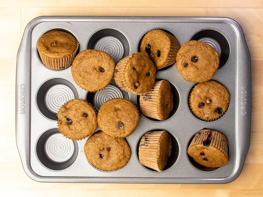 same Circulon muffin tin with baked muffins in a haphazard pile on top, with some muffins still in the wells they were baked in