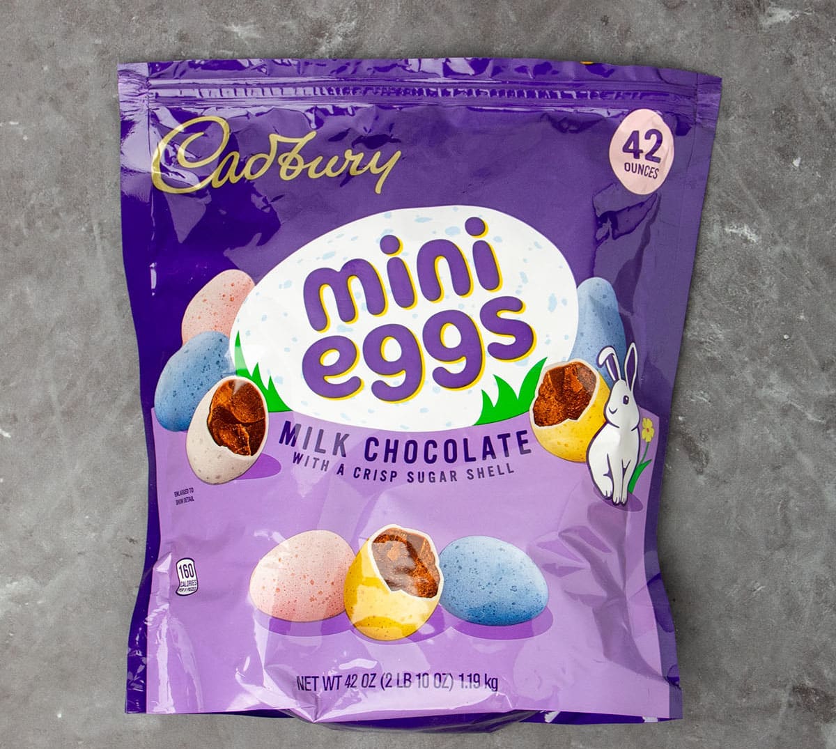 large plastic purple pouch of Cadbury brand mini egg chocolate candies on black marble background