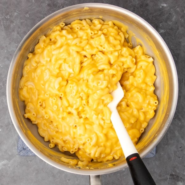 overhead closeup image of round metal saucepan with yellow-orange dairy free elbow macaroni with cheese sauce