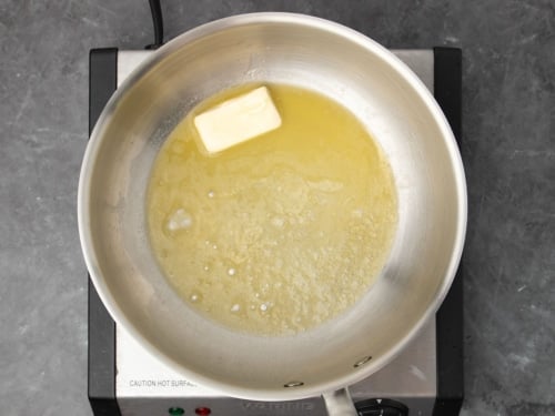 round flat, wide metal saucepan with partially melted butter bubbling