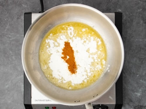 same saucepan with white flour and dark orange-brown paprika powder on top of melted butter