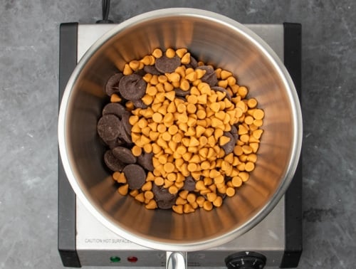 round metal mixing bowl with dark brown chocolate disks and light brown butterscotch chips