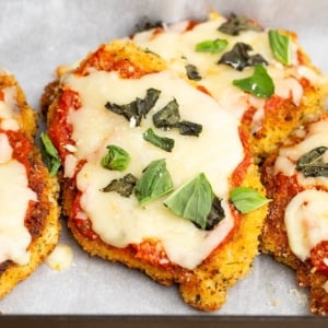 gluten free chicken parmesan with chopped fresh basil on white paper in black casserole dish