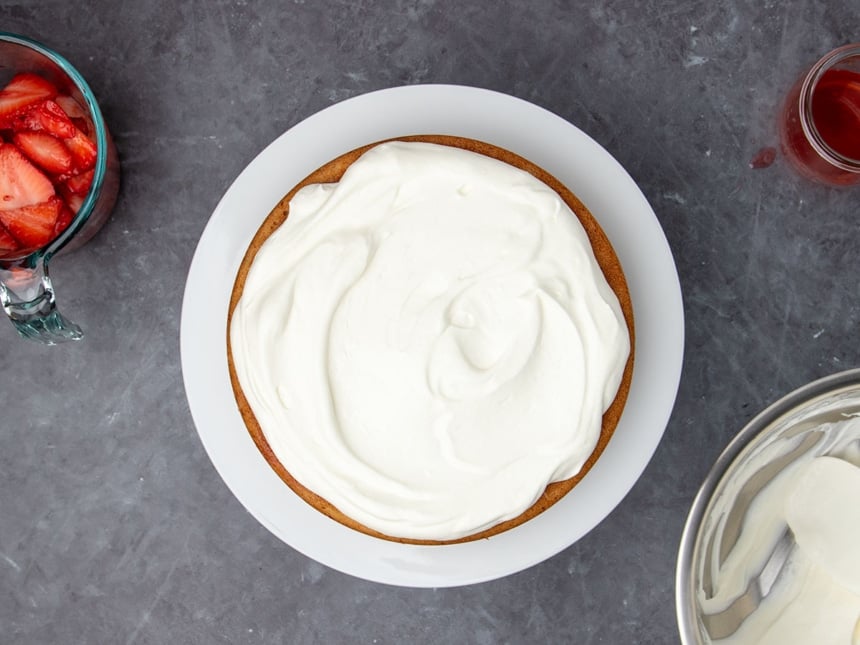 swirled layer of white whipped cream on top of light brown cake on cake plate