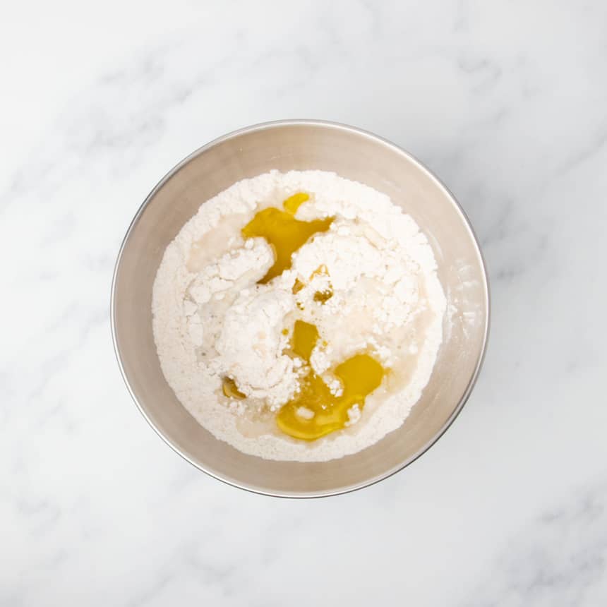 same bowl with yellow olive oil added on top of water over flour